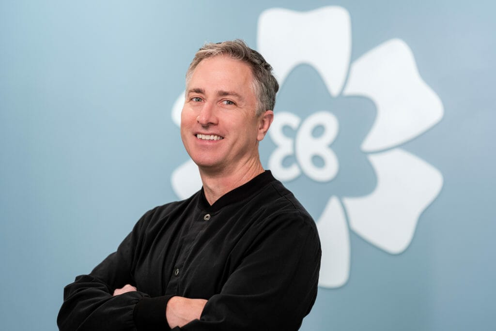 Dr. Batterton posing in front of logo in Delware OH dental office