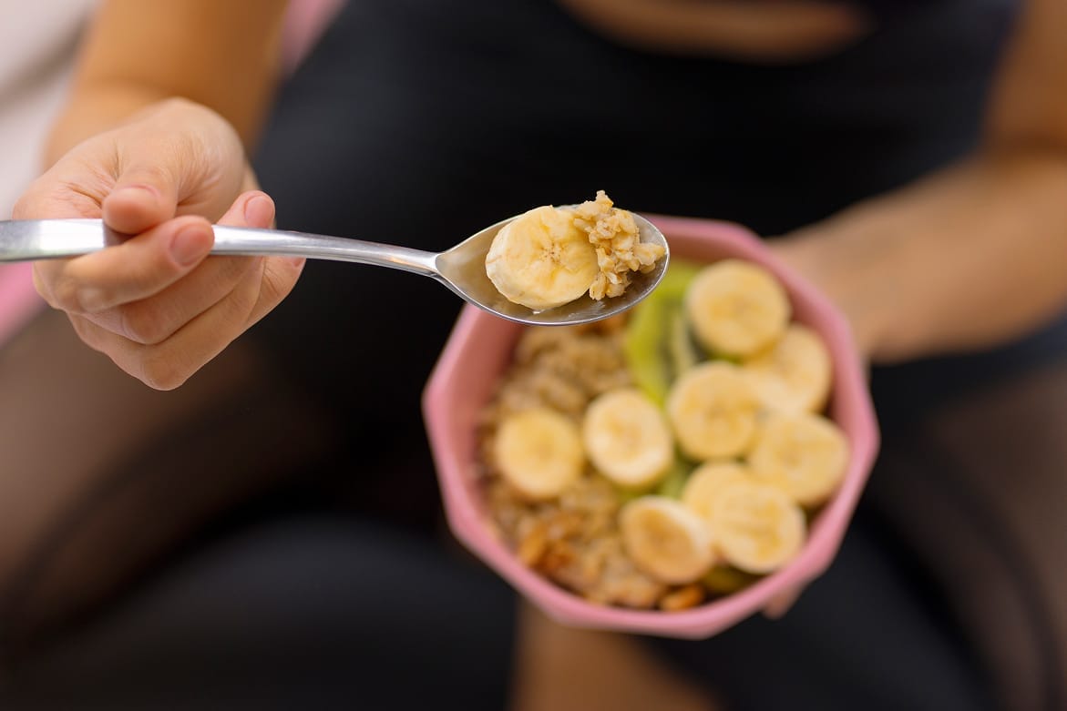 Close-up of spoon in bowl with banana slices and cereal.